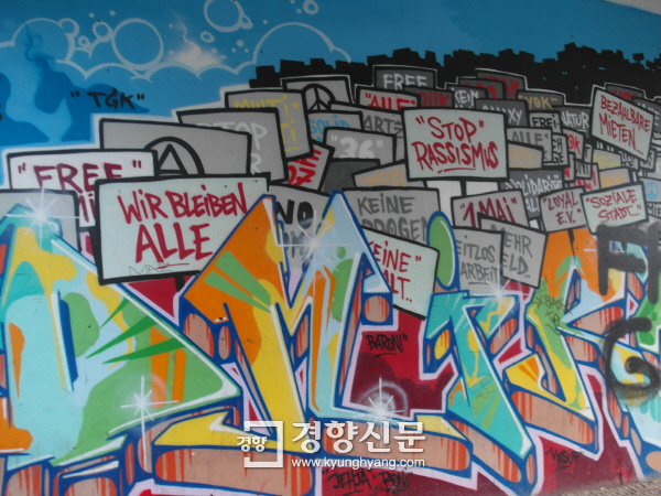 독일 베를린 크로이츠베르크 코트부서토어에서 있는 코티운트코 사무실 근처 벽에 그려진 벽화에 “우리가 모두 여기에 머물고 있다(WIR BLEIBEN ALLE)” 등의 문구가 적혀 있다. ‘집값이 오르는데 반대하는 것은 당신만이 아니다’ ‘아래로부터의 도시가 구현돼야 한다’ 등 문구가 적힌 그라피티도 많았다. &nbsp;베를린 | 김세훈 기자